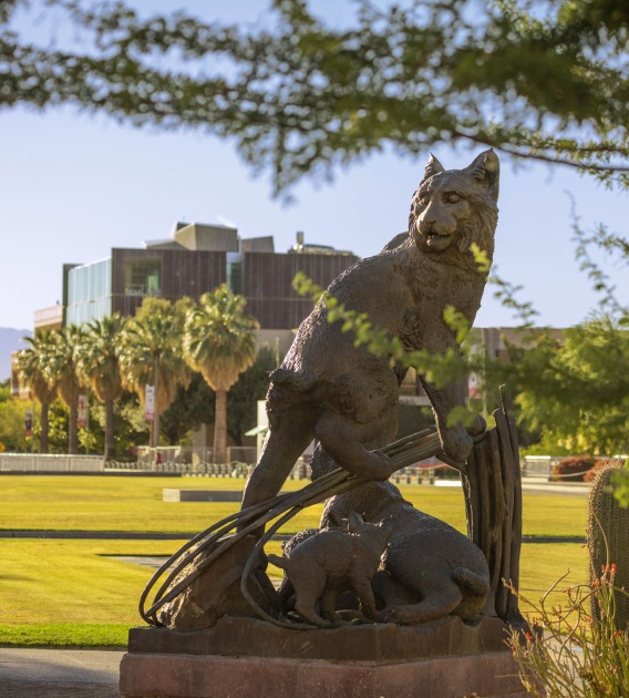 a statue of a bobcat with a field of grass in the background